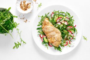 Baked chicken breast coated in Paleo bread crumbs served with fresh arugula salad