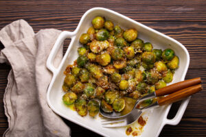 Crohn's friendly roasted Brussels sprouts glazed with balsamic vinegar, honey, mustard, and orange juice in a white baking dish