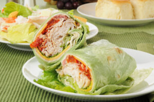 Paleo crab salad wrap with avocado, cilantro, and fresh vegetables, served with lime and side salad