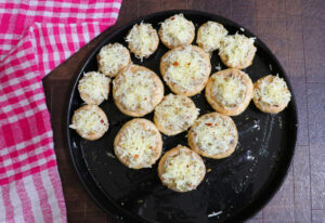 Baked Paleo crab-stuffed mushrooms on a black tray topped with golden melted topping