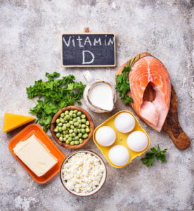 Vitamin D rich foods including salmon, eggs, milk, cheese, peas, and fresh parsley