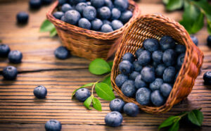 Paleo baking with fresh blueberries in baskets on a wooden surface.