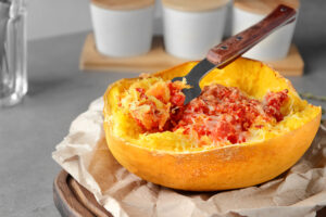 Baked spaghetti squash served in its shell, scraped into pasta-like strands with tomato sauce on top