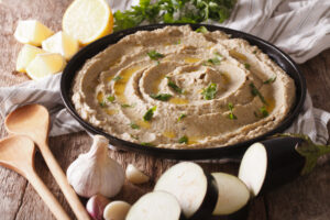 Bowl of Paleo Baba Ghanoush made with roasted eggplant, tahini, garlic, and olive oil, garnished with parsley and drizzled with olive oil.