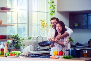 Happy couple cooking stir fry vegetables in a bright kitchen