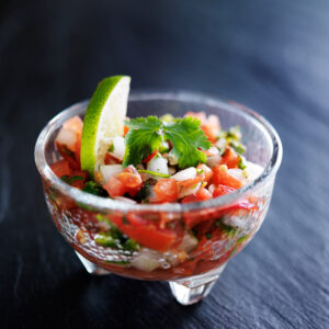 Fresh Paleo pico de gallo salsa in a glass bowl with lime wedge and cilantro garnish