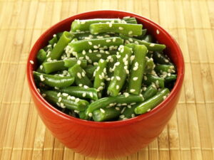 Crohn’s-friendly sesame green beans served in a red bowl, topped with sesame seeds