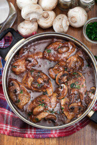 Skillet of Paleo Chicken Marsala with mushrooms and spinach in a rich wine sauce.