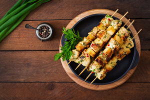 Grilled Paleo chicken skewers with fresh herbs on a black plate