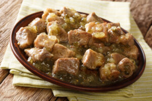 Paleo chili verde with pork chunks simmered in tomatillo and green chile sauce, served on a rustic plate.