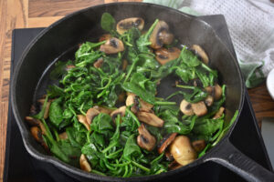 Paleo spinach and mushrooms sautéed with garlic and onion in a cast iron skillet.