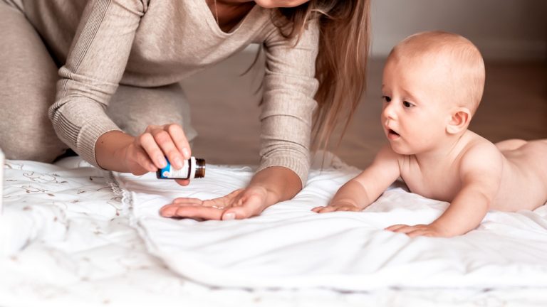 Mother giving medicine to infant, illustrating early-life antibiotic use and its connection to allergy and asthma risk.